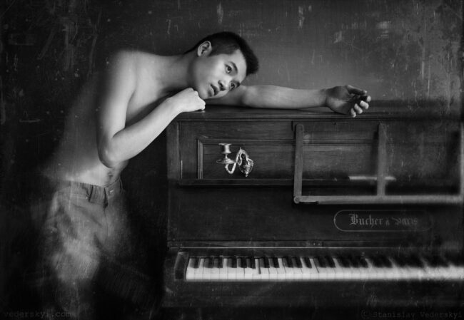 young male leaning on piano. Muddy photosession for musician in black and white colours. stylized as old vintage photo