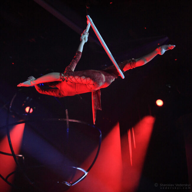 aerial acrobat lady in red costume flying on hoop in the show