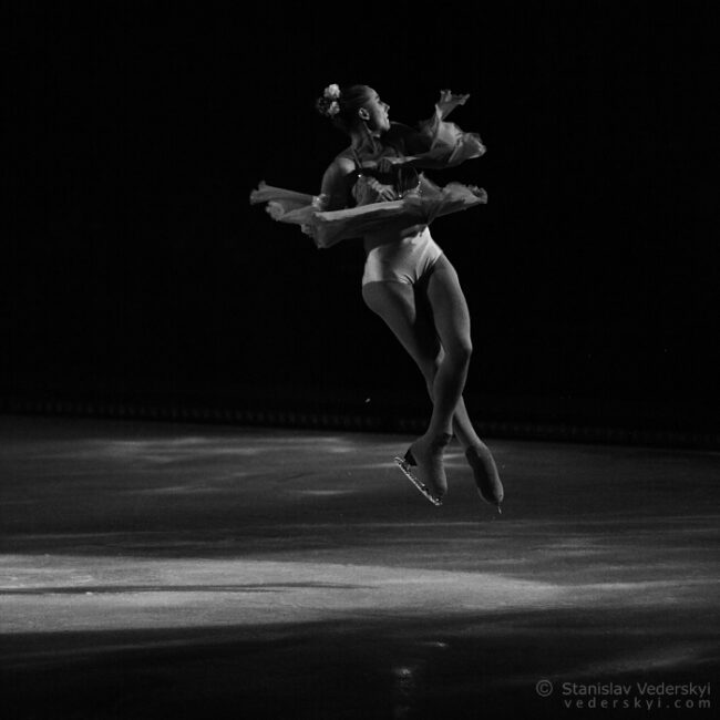 beautiful young lady figure skater performing jump in ice show