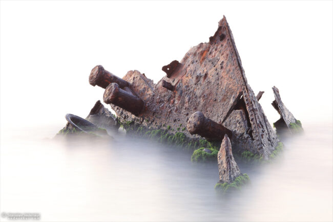 Rusty ship wreck in the sea. Long exposure turned water to the mist.
