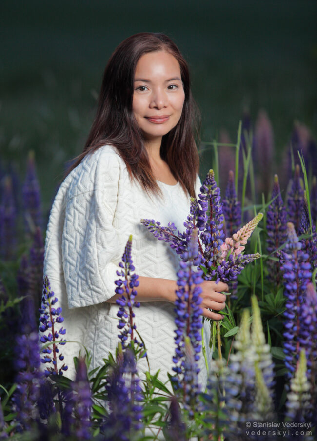 lady in field with lupins at sunset time