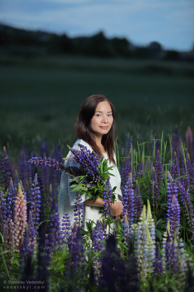 lady in field with lupins at sunset time